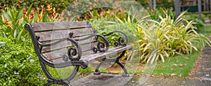 A wooden bench in the middle of beautiful blooming ornamental flower gardens of a natural public park in the Summer or Spring
