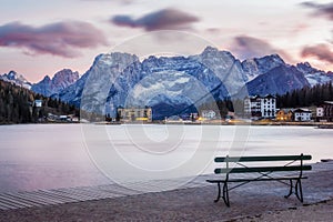 Wooden bench near famous tourist place Lake Lago di Misurina on sunset. picture with long e[posure and amazing dramatic sky photo