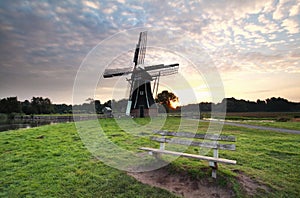 Wooden bench near windmill at sunrise