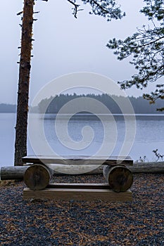 Wooden bench next to a blue misty lake in Finland photo
