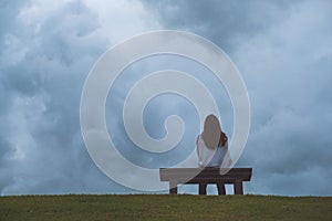 A wooden bench in the park with cloudy and gloomy sky background