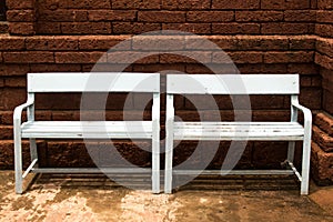 Wooden bench on red brick wall background.