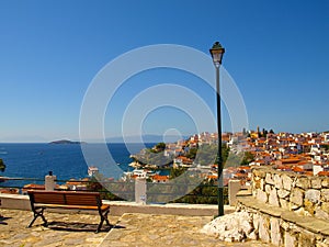 Wooden bench and street lamp with panoramic view over The Aegean Sea and Skiathos, Greece