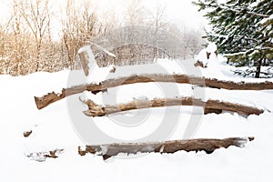 Wooden bench in winter city park is covered with snow
