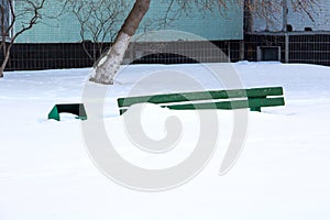 Wooden bench in winter under the snow, inaction of snow blowers in the snowfall