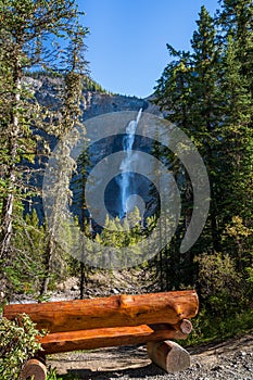 Wooden bench by the Yoho River over Takakkaw Falls in a summer day. Yoho National Park, Canadian Rockies.