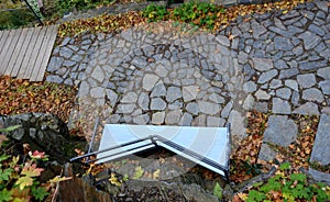 Wooden benches of irregular geometric polygons on stone gray pavement in a park with low retaining walls stacked of porphyry. orna