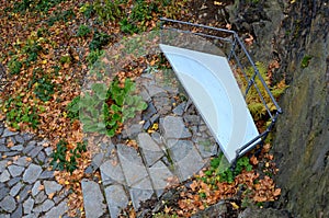 Wooden benches of irregular geometric polygons on stone gray pavement in a park with low retaining walls stacked of porphyry. orna