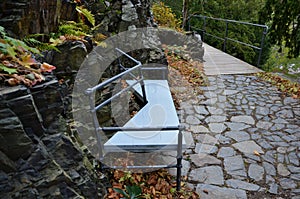 Wooden benches of irregular geometric polygons on stone gray pavement in a park with low retaining walls stacked of porphyry. orna