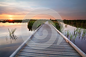 Wooden bike path on water at sunset