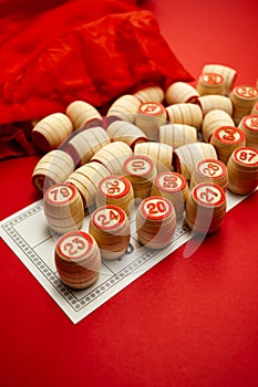 Wooden bingo kegs, on a red background in a red bag, for playing bingo. A way to spend time at home. A game of chance
