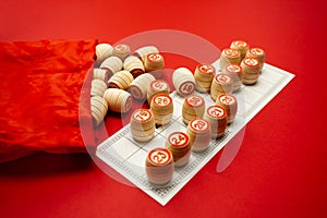 Wooden bingo kegs, on a red background in a red bag, for playing bingo. A way to spend time at home. A game of chance