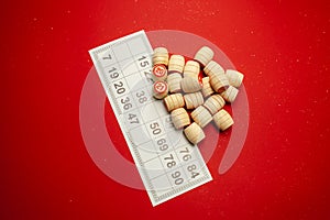 Wooden bingo kegs, on a red background in a red bag, for playing bingo. A way to spend time at home. A game of chance