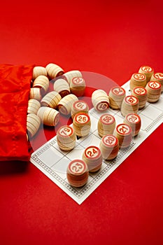 Wooden bingo kegs, on a red background in a red bag, for playing bingo. A way to spend time at home. A game of chance