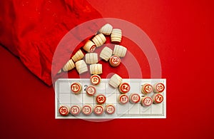 Wooden bingo kegs, on a red background in a red bag, for playing bingo. A way to spend time at home. A game of chance