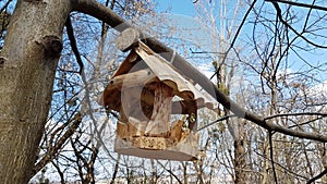 Wooden bird feeder made of wood in the style of houses from a log house. Decorative design of parks and recreation areas. Handmade
