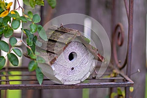 Wooden bird house standing on a metal rustic shelf