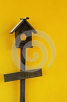 Wooden bird house with yellow wall