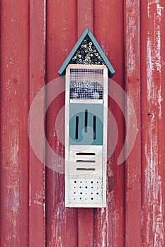 Wooden birdhouse with fine details on red wall