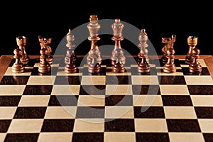 Wooden black chess figures on a chessboard