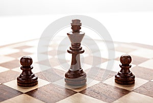 Wooden black chess king between black pawns