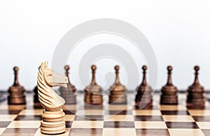 Wooden black and white chess pieces on a chessboard, horse and pawns on the background, leadership retro concept