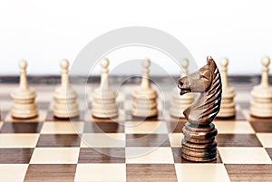 Wooden black and white chess pieces on a chessboard, horse and pawns on the background, leadership retro concept