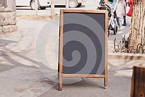 Blackboard in front of restaurant entrance. Mock up menu blank board sign stand near shop or cafe restaurant. Street