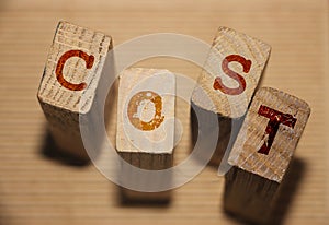 Wooden block with alphabet combine word COST, Cost, expense or company profit and loss concept, analyze spending or payment