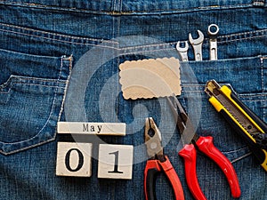 Wooden block calendar 1 May and Joinery tools on a jean texture