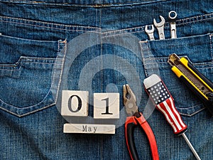 Wooden block calendar 1 May and Joinery tools on a jean texture