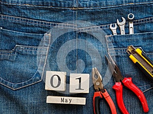 Wooden block calendar 1 May and Joinery tools on a jean texture