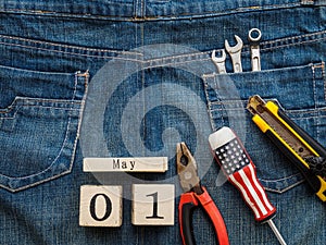 Wooden block calendar 1 May and Joinery tools on a jean texture