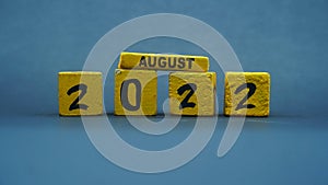 Wooden block calendar for August 2022. Yellow on a dark background