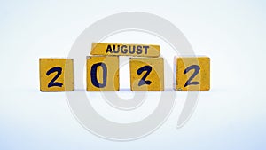 Wooden block calendar for August 2022. Yellow on a white background