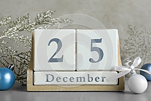 Wooden block calendar and Christmas decor on light grey stone table. Holiday celebration