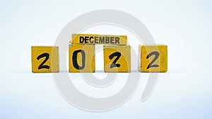 Wooden block calendar for December 2022. Yellow on a white background