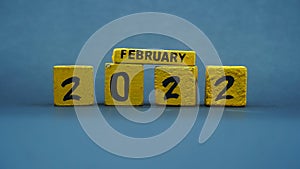 Wooden block calendar for February 2022. Yellow on a dark background