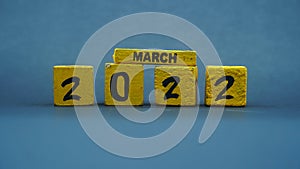 Wooden block calendar for March 2022. Yellow on a dark background