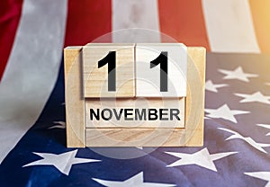 Wooden block calendar for November 11, USA Veterans Day, with Stars and Stripes usa flag on background