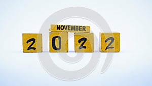 Wooden block calendar for November 2022. Yellow on a white background