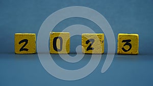 Wooden block calendar with numbers for 2023. Yellow on a dark background