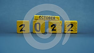 Wooden block calendar for October 2022. Yellow on a dark background