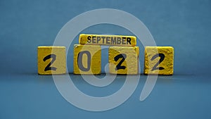 Wooden block calendar for September 2022. Yellow on a dark background
