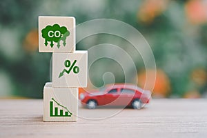wooden block with co2 reduction icon concept and blurred miniature car  for CO2 emission ,green industries business . Net