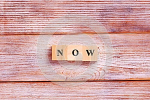 Wooden block cube for Now wording on white background. Concept of time management or living in present moment photo