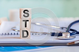 Wooden block form the word STD with stethoscope on the doctor`s desktop. Medical concept