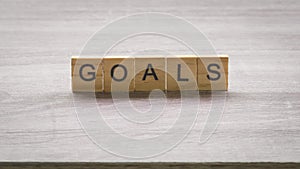 Wooden block with goals massage on wood table background.