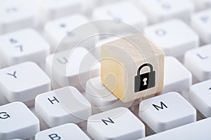 Wooden block with lock graphic on computer keyboard.