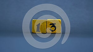 Wooden block with number 13. Yellow color on dark background